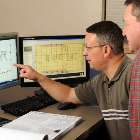 A contractor and an architect discussing a project while pointing at a computer.