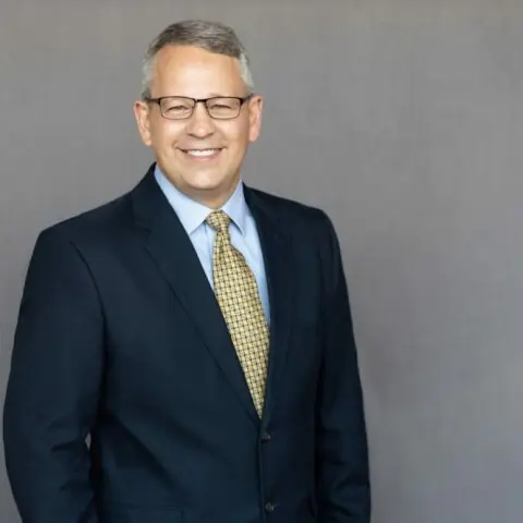 Portrait of James Williams, Senior Project Manager, in a professional setting smiling wearing a suit.