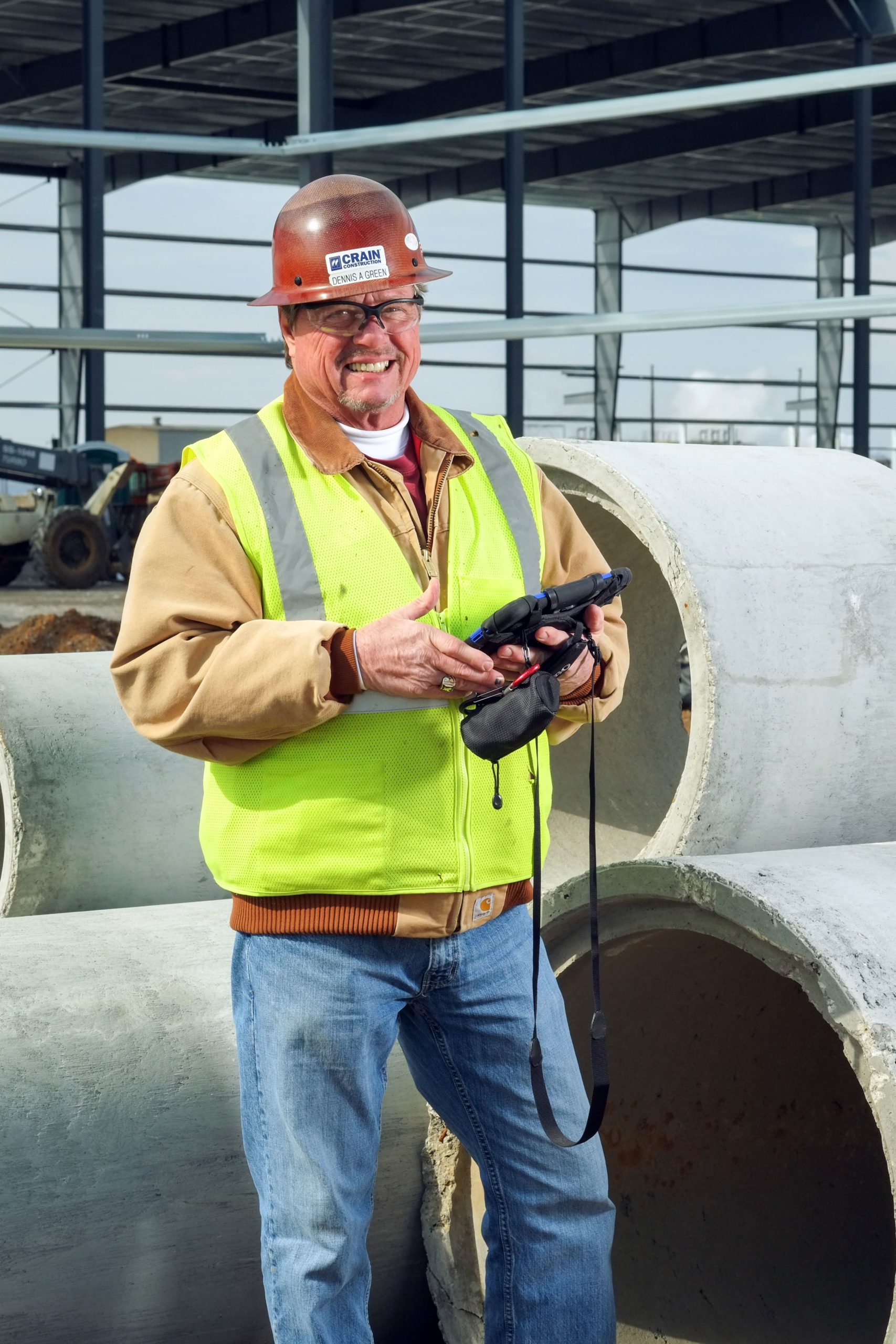 Crain employee smiling while holding an iPad on a construction site