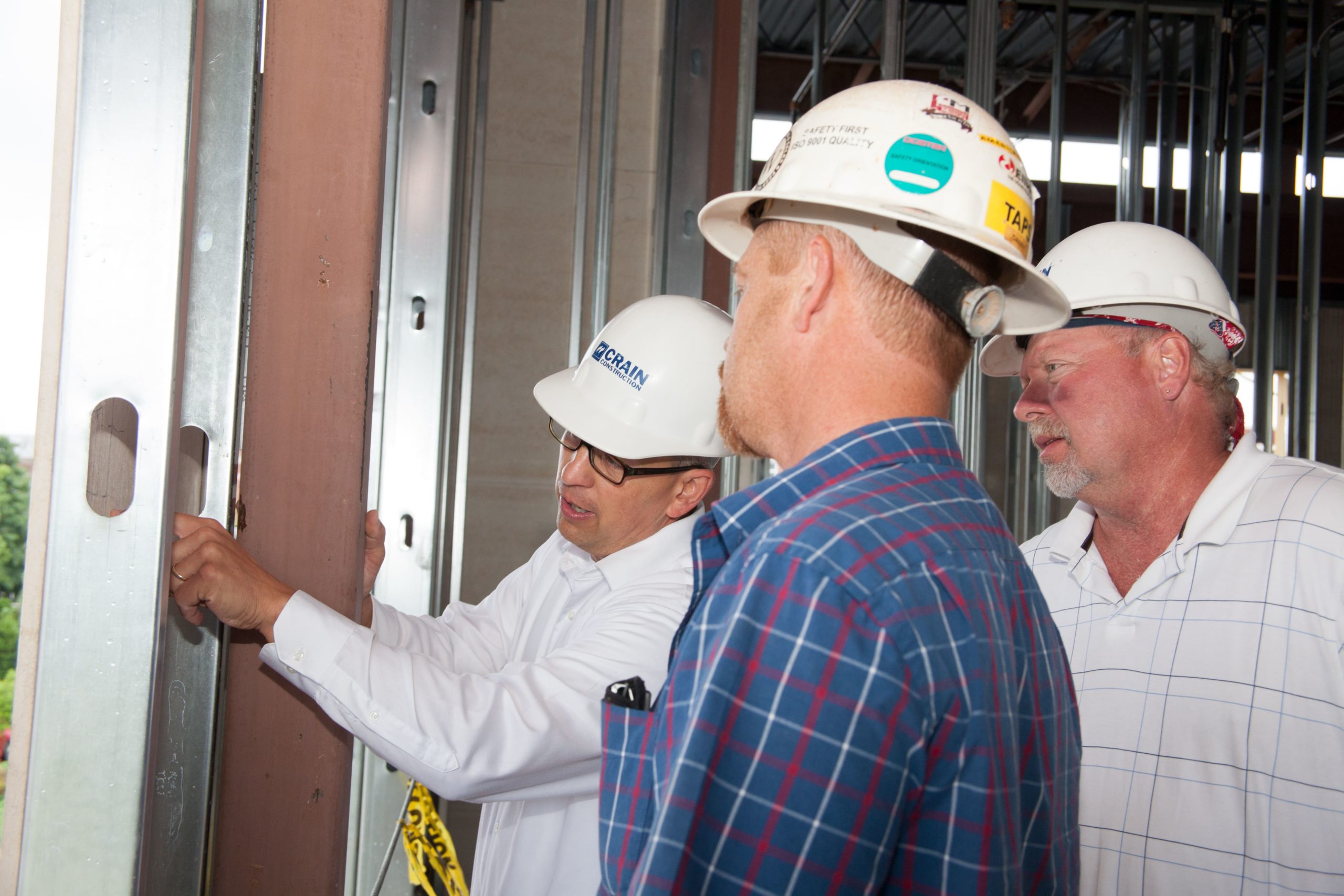 3 Crain employees inspecting a wall on a construction site