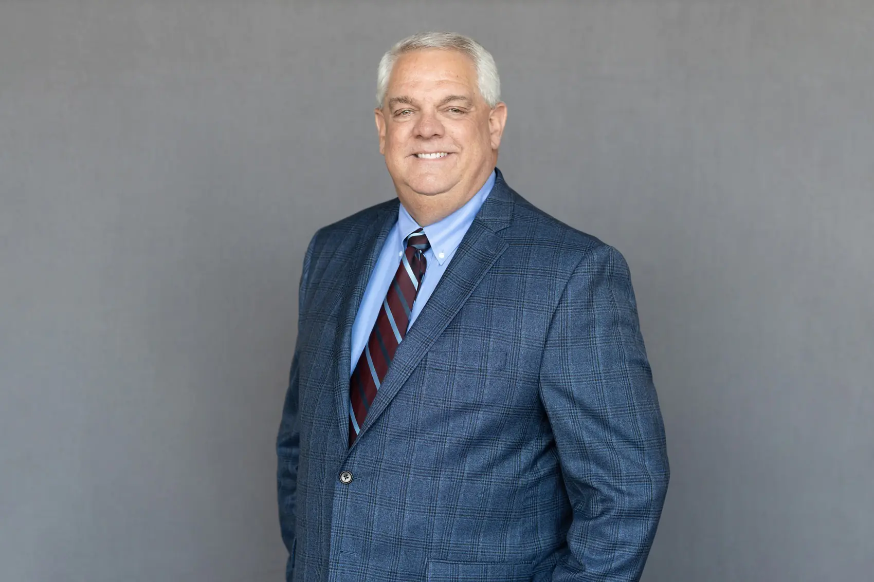 Portrait of Jim Pedigo wearing professional attire, with a friendly smile, in a well-lit indoor setting.
