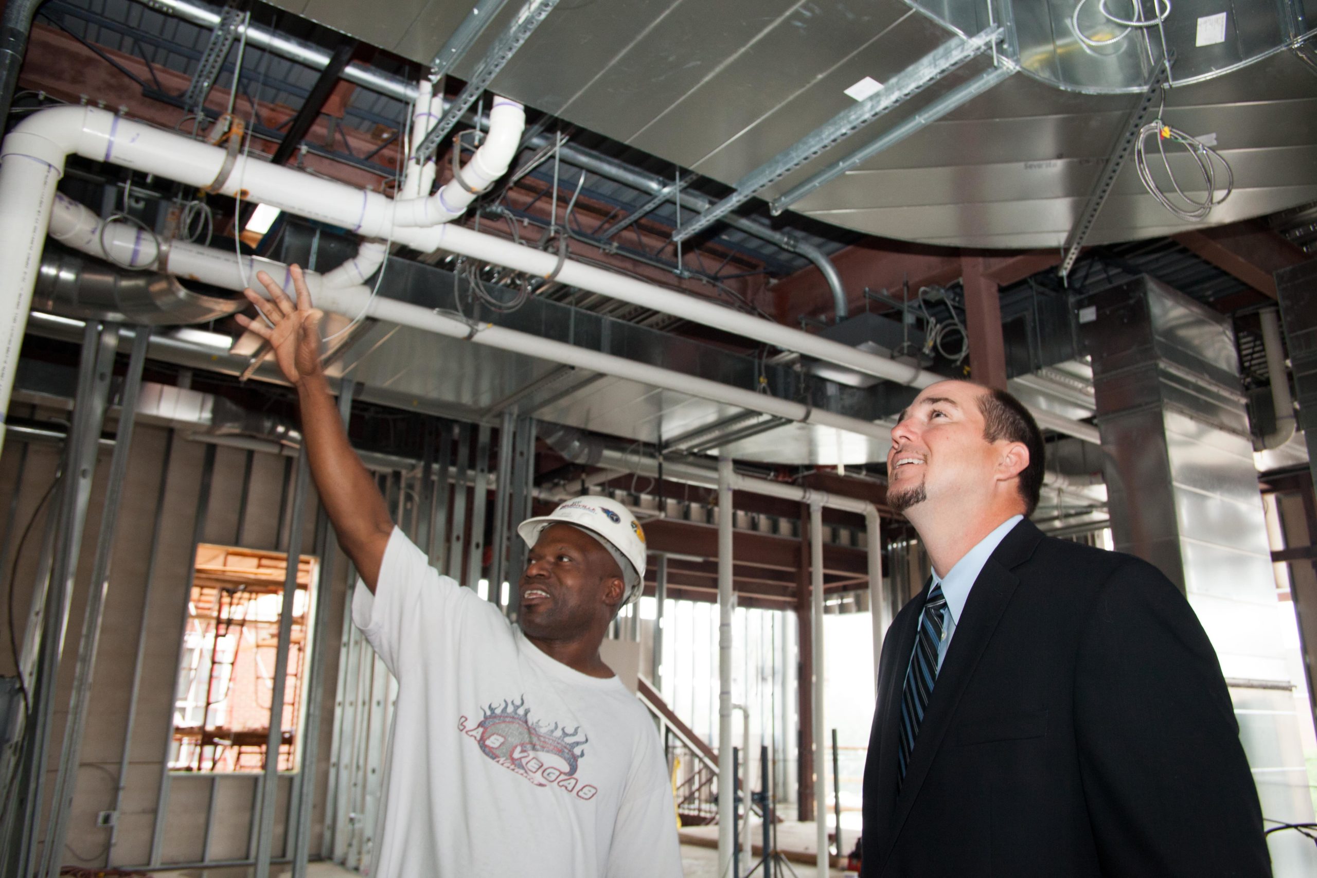 construction worker showing project under construction to man in suit