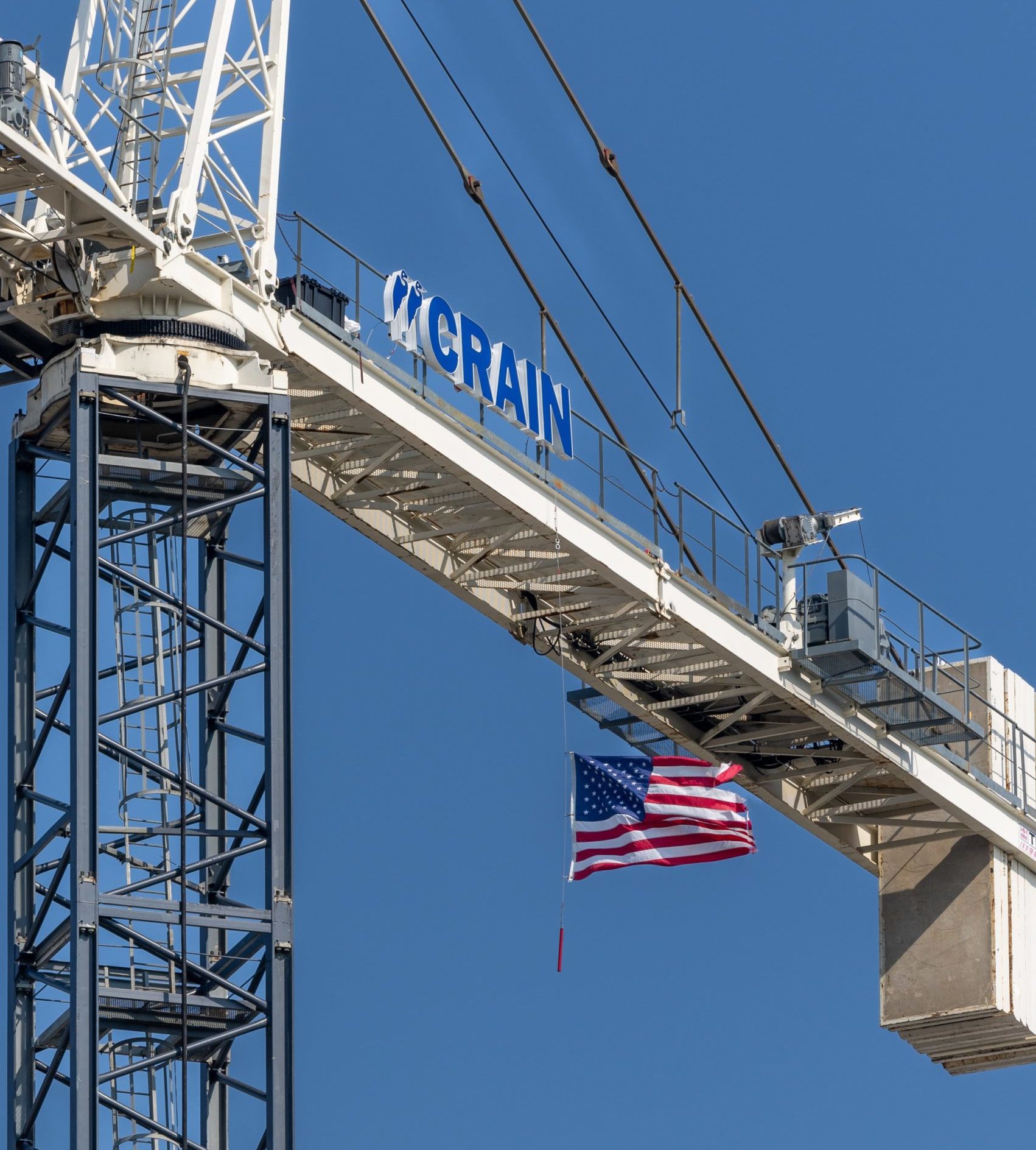 American flag hanging from a Crain Construction crain.