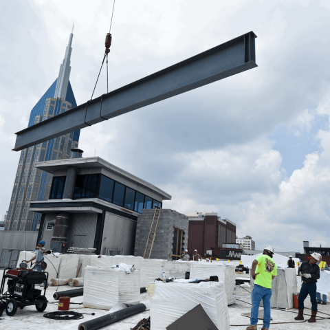 crane holding beam above commercial construction site