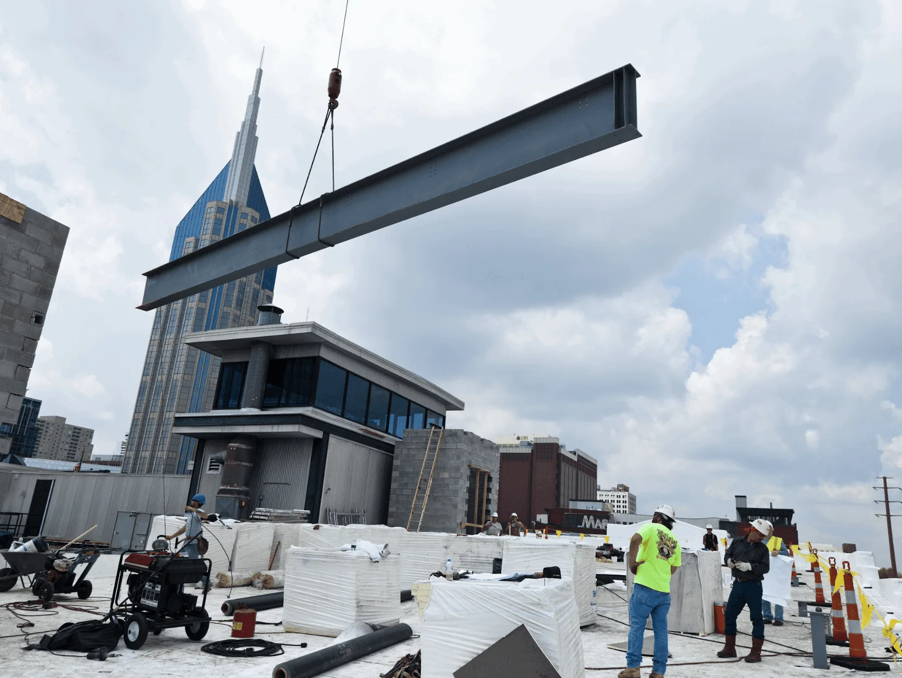 crane holding beam above commercial construction site