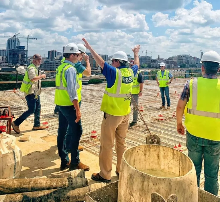 A group of construction workers, one raising his arms, on a job site.
