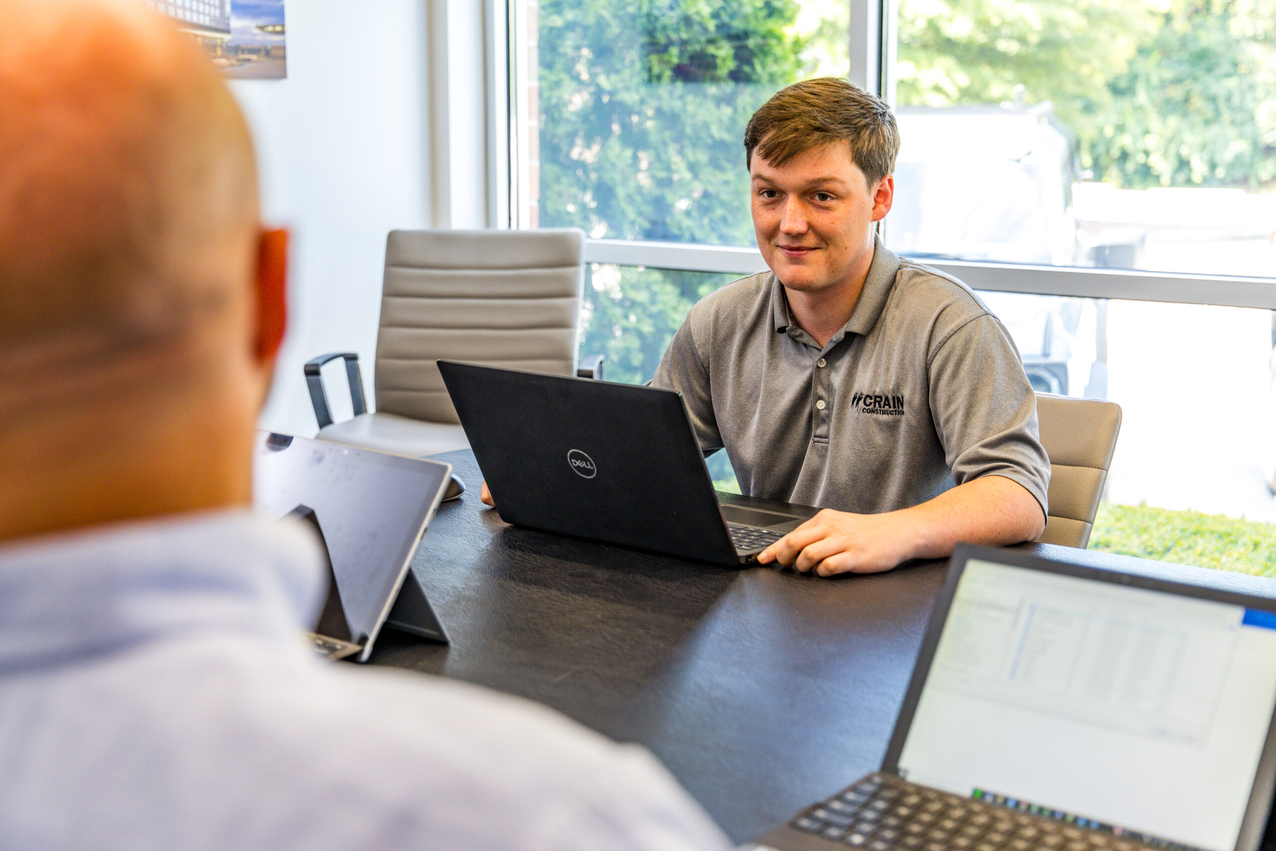 crain construction employees meeting in a conference room with laptops