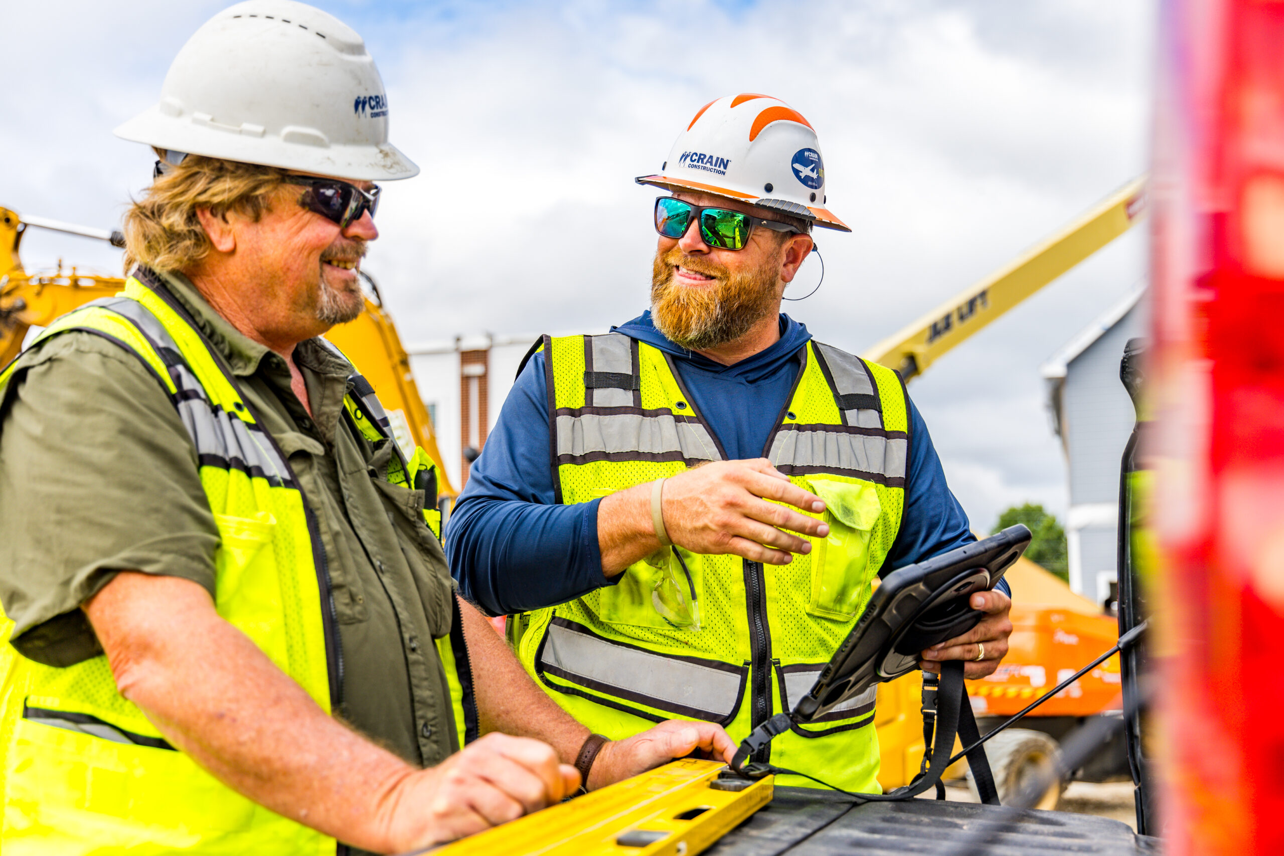crain construction workers on site wearing hard hats and vests